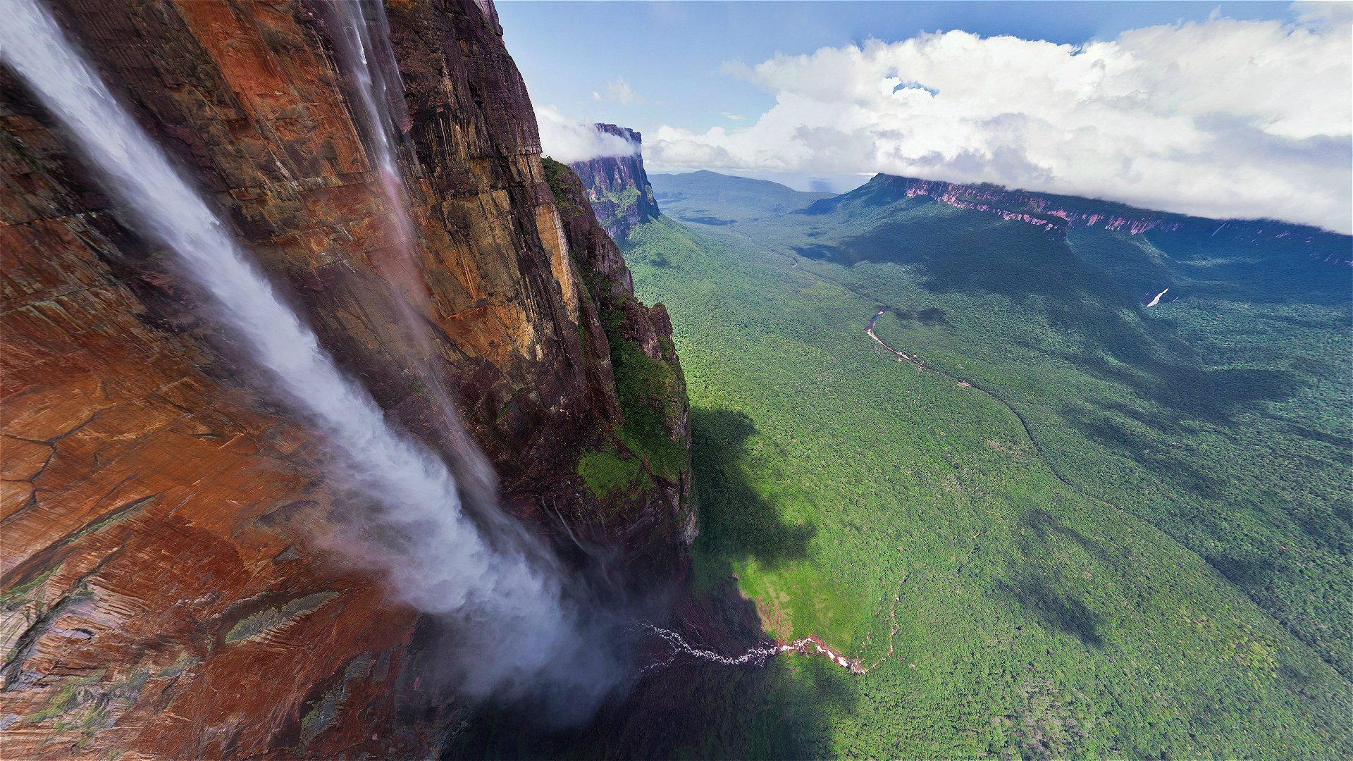 High waterfall with mountains, greenery and clouds