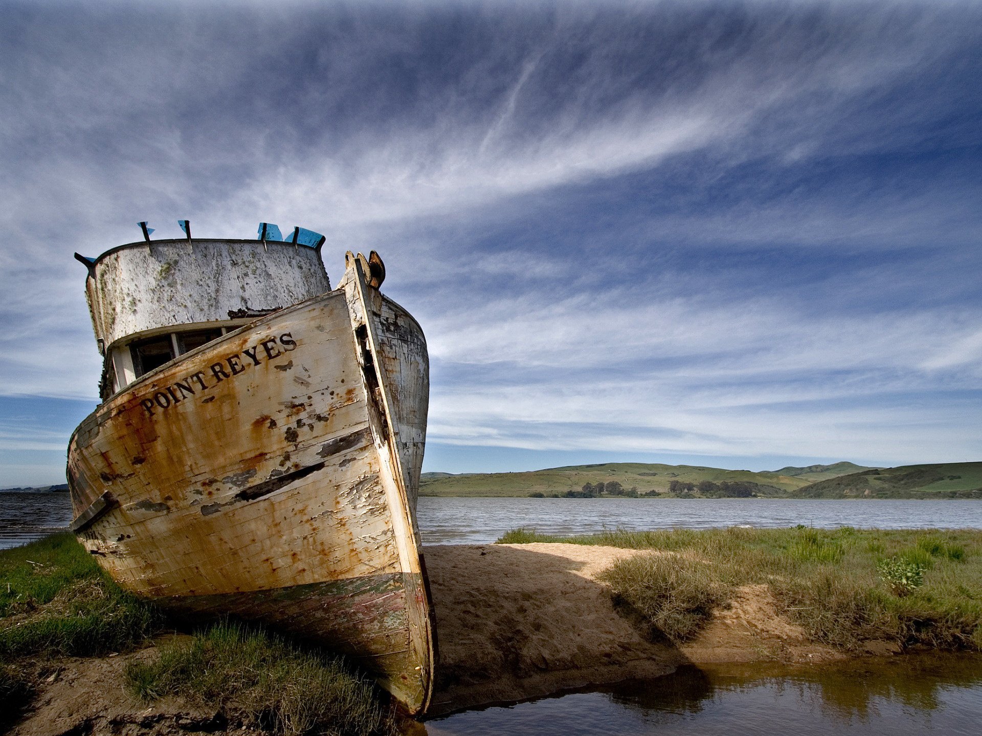 An old ship on the shore under a blue sky