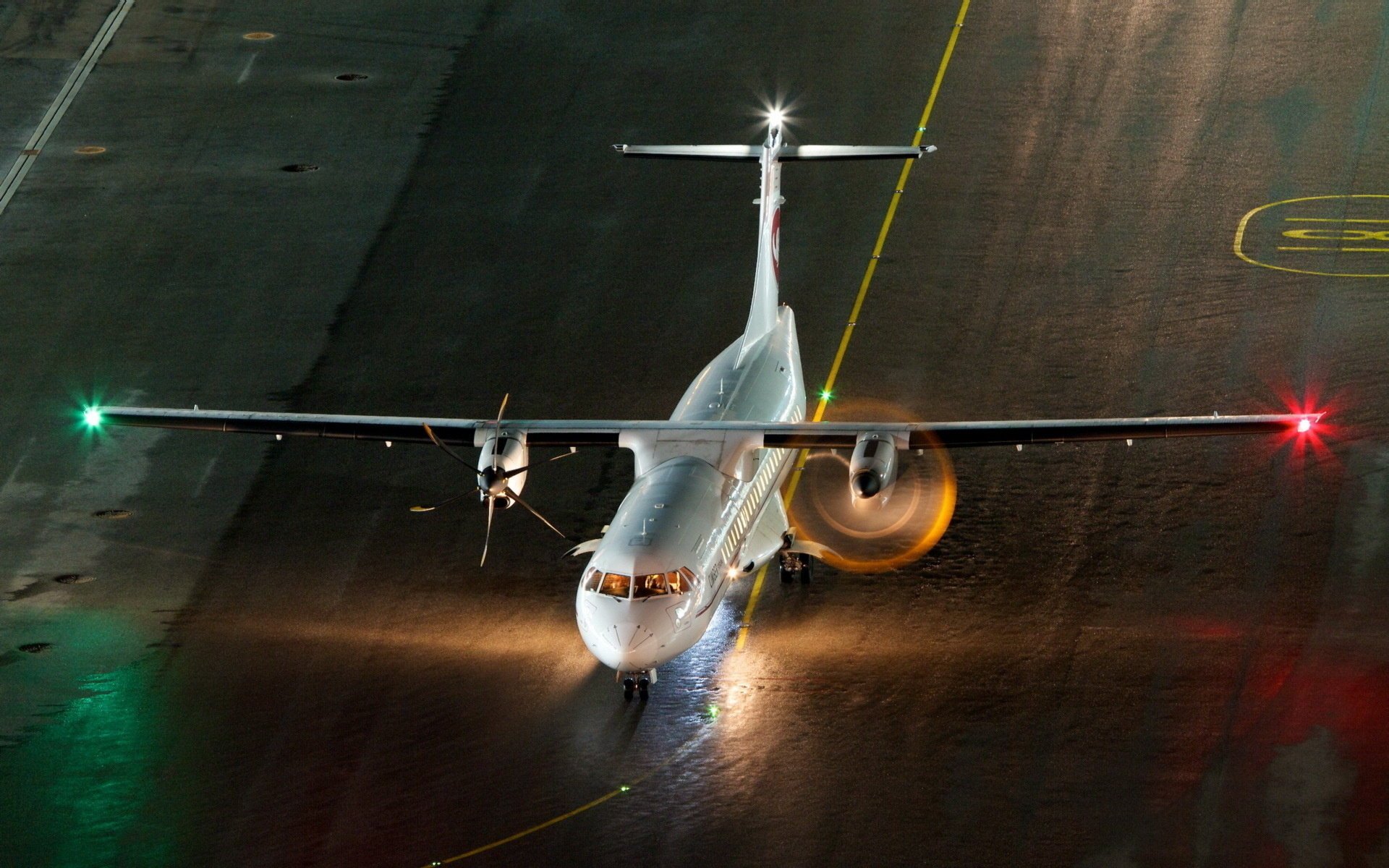 A plane with burning lights at the airfield at night