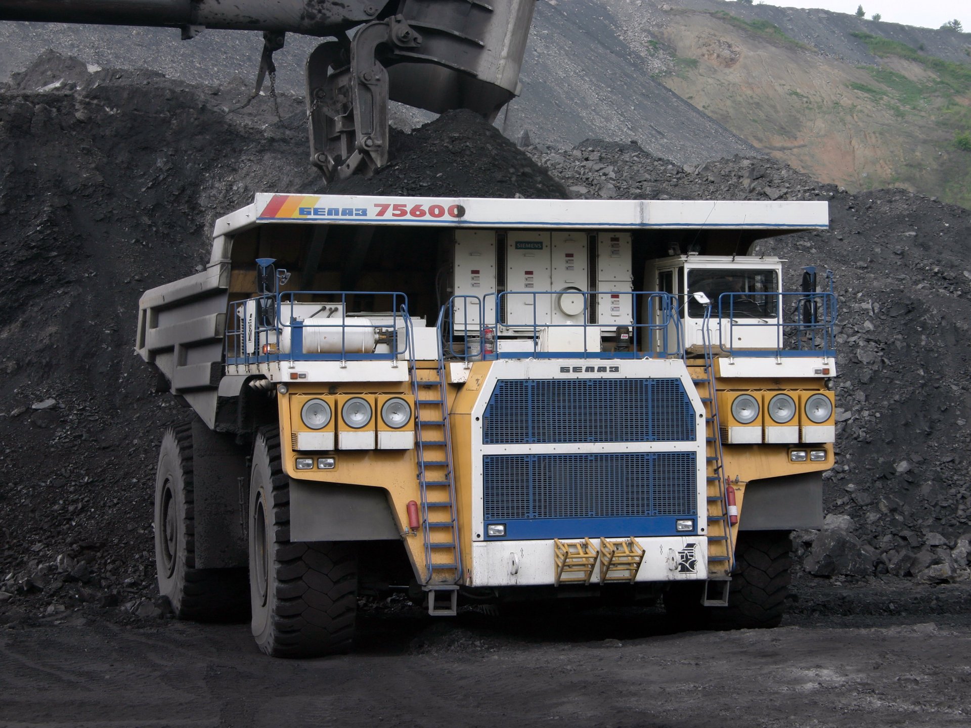 Dump truck in the process of working in coal and dust