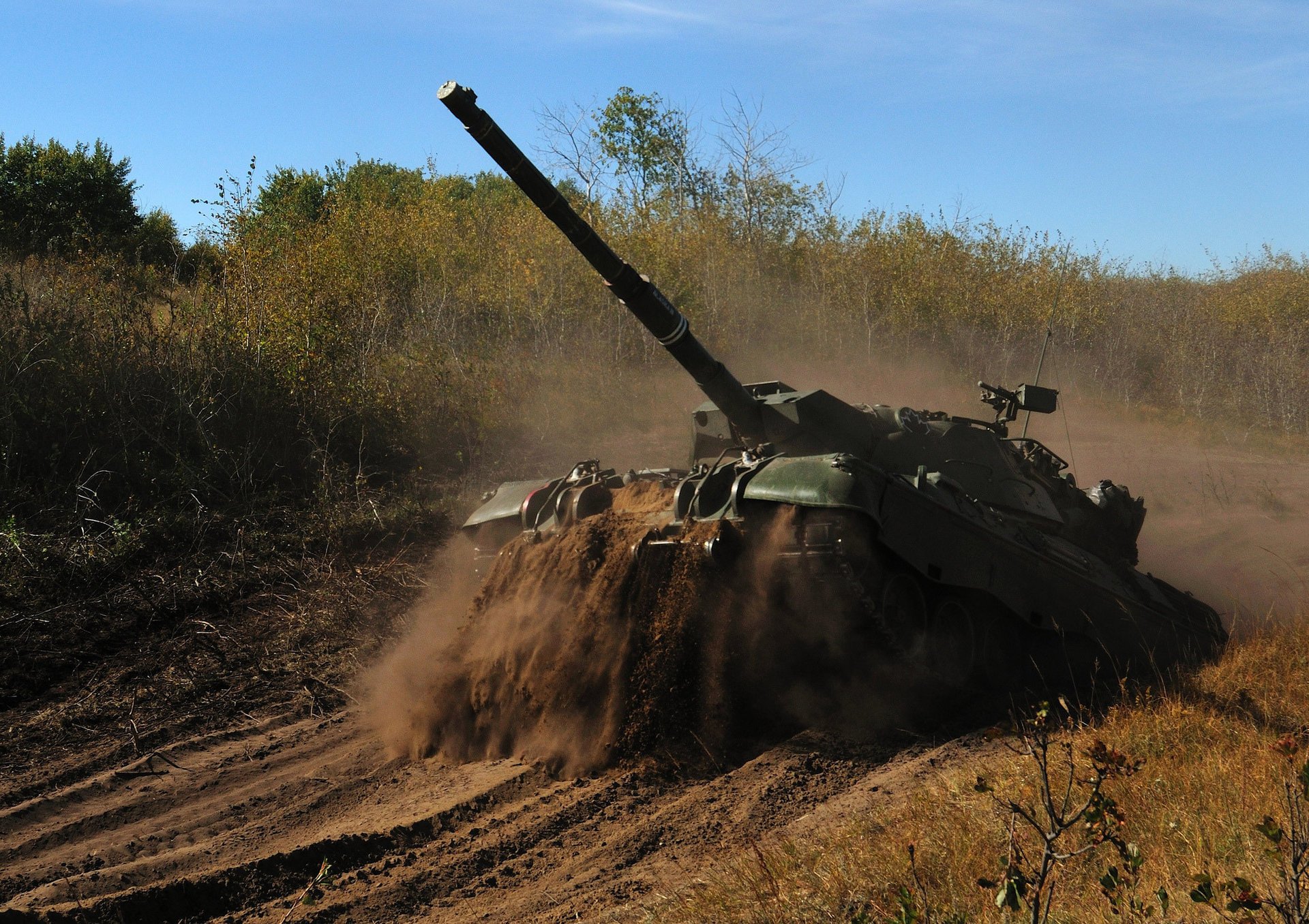 A battle tank moves across the sand